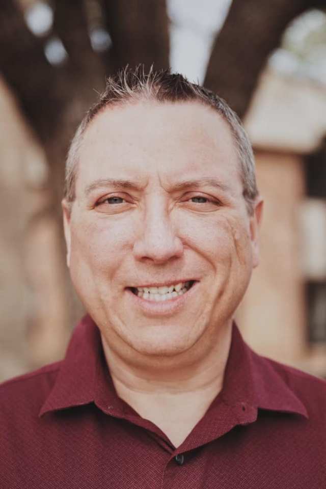 Christian's professional headshot for Kingwood Counseling Center. He is squinting into the sun with a big smile on his face